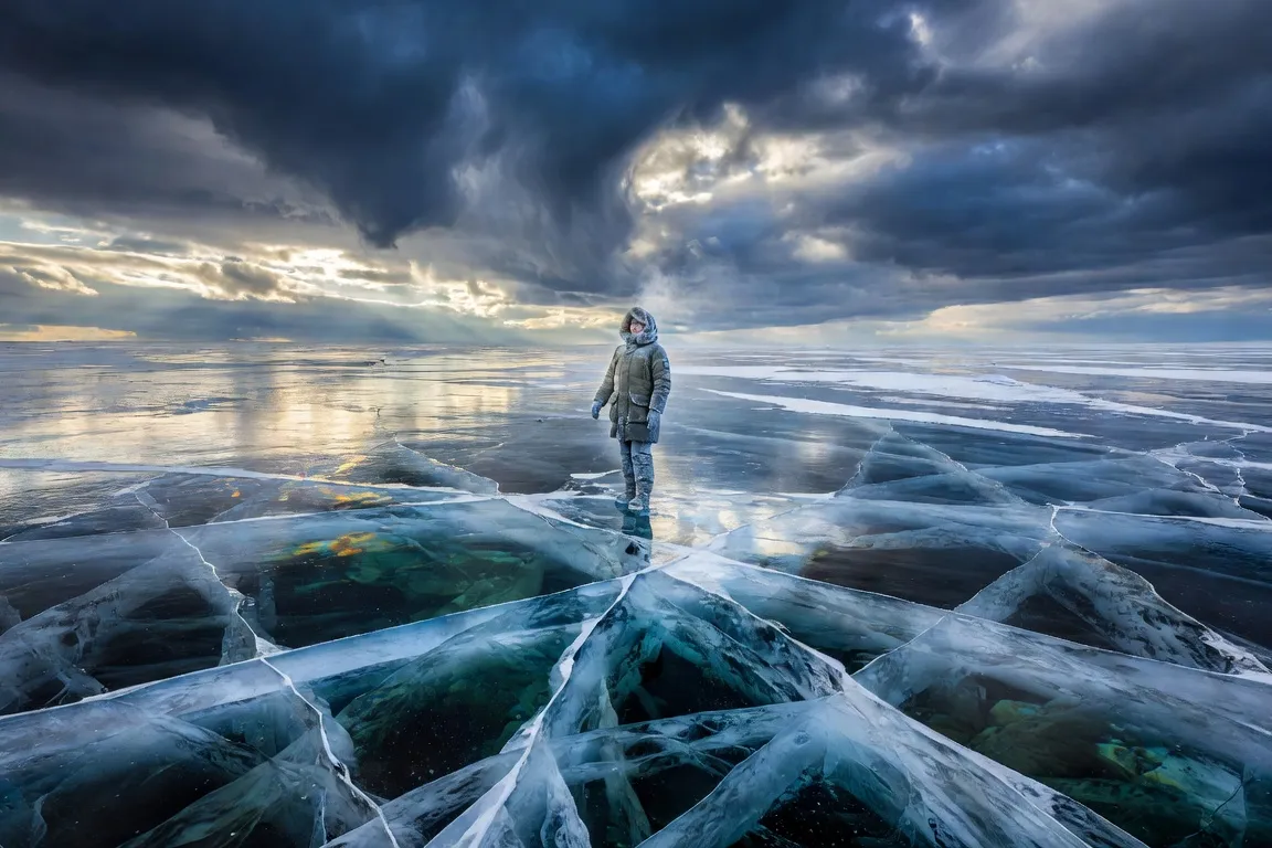 Surface du lac Baïkal en hiver, glace bleue-verte transparente, personnage debout sur la glace